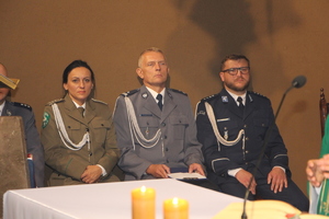 Przedstawicielka Straży Granicznej oraz dwóch policjantów, którzy uczestniczą we Mszy Świętej siedzą obok ołtarza.