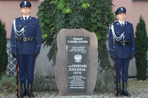 Dwóch umundurowanych policjantów tworzy warte honorową przy obelisku śp. sierż. Grzegorza Załogi.