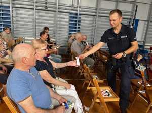 Policjant rozdaje wizytówkę do kontaktu uczestnikom spotkania.