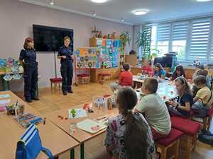 Policjantki prowadza prelekcję przed grupą dzieci.