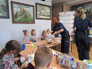 Policjantki rozdają dzieciom ulotki związane z bezpieczeństwem.