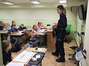 Policjantka stoi w klasie przed grupą uczniów.