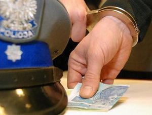 Policyjna czapka i dłoń trzymająca banknot
