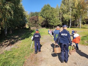 Policjantki wraz z dziećmi i wychowawcami zmierzają na polane celem posadzenia drzewek.