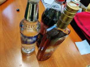 Zdjęcie przedstawiające trzy butelki na biurku. Dwie są z alkoholem.