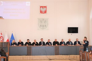 Grupa osób, na czele ze Starostą Będzińskim i Komendantem Powiatowym Policji w Będzinie siedzących na sali sesyjnej podczas debaty społecznej.