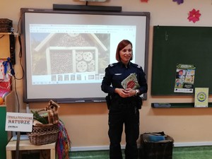 Na zdjęciu policjantka znajduje się w klasie, prezentuje rekwizyty dotyczące kampanii &quot;Naturalnie,że chronimy&quot; oraz omawia przygotowaną prezentację.