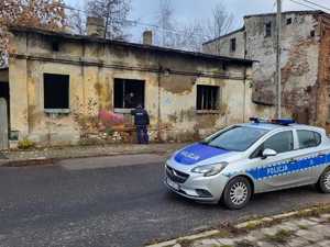 Zdjęcie przedstawiające policjantów kontrolujących pustostany. Z przodu znajduje się radiowóz.