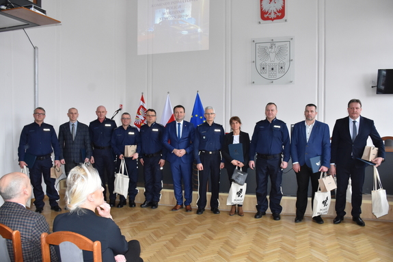 Na zdjęciu grupa osób w sali sesyjnej w Starostwie Powiatowym w Będzinie na czele z I Zastępcą Komendanta Wojewódzkiego Policji.