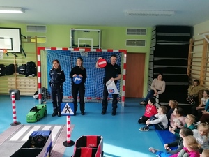 Na zdjęciu umundurowani policjanci prowadzący prelekcje w Zespole Szkół Specjalnych nr 5 w Dąbrowie Górniczej z wykorzystaniem mobilnego miasteczka ruchu drogowego.