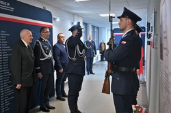 Zdjęcie. Widoczni umundurowani policjanci i uczestnicy uroczystości stojący w korytarzu.