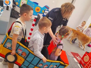 Na zdjęciu policjantka z dziećmi, które mają założone autochodzik ucząc się przepisów w praktyce.