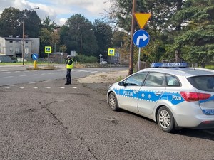 Na zdjęciu radiowóz policyjny, a obok niego umundurowany policjant.