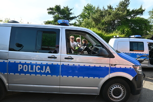 Na zdjęciu do radiowozu policyjnego wchodzi dziecko z rodzicami.