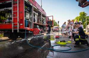 Na zdjęciu widzimy wóz strażacki, strażaka z grupą dzieci.