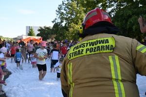 Na zdjęciu strażak lejący pianę gaśniczą na festynie dla dzieci.
