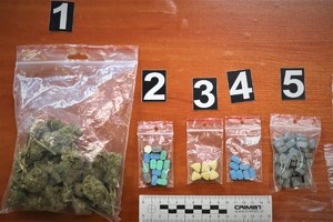 Na zdjęciu zatrzymane przez policjantów narkotyki, które ułożone są na biurku. Po lewej stronie marihuana, obok znajdują się kolorowe tabletki.