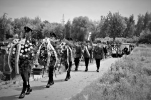 Na zdjęciu widzimy utworzony kondukt na cmentarzu, na czele z umundurowanymi policjantami, którzy niosą wieńce.