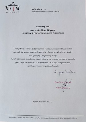 Zdjęcie przedstawia życzenia od Rafała Adamczyka Posła na Sejm Rzeczpospolitej Polskiej Szanowny Pan insp. Arkadiusz Więcek Komendant Powiatowy Policji w Będzinie. Z okazji Święta Policji życzę wszystkim Funkcjonariuszom i Pracownikom satysfakcji z wykonywanych obowiązków, zdrowia, wszelkiej pomyślności oraz spokojnej i bezpiecznej służby. Państwa formacja mundurowa zawsze cieszyła się wysokim poziomem zaufania społecznego, bo wynikało to bezpośrednio z Waszego zaangażowania, wysokiego poziomu empatii i tolerancji. Z poważaniem Poseł na Sejm RP Rafał Adamczyk. Będzin, dnia 11.07.2023 r.