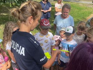 Zdjęcie, na którym policjantka rozdaje dzieciom odblaski.