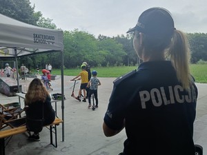 Na zdjęciu policjantka przygląda się jak młodzież korzysta z skateparku.