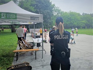 Zdjęcie, na którym policjantka stoi i przygląda się jak dzieci korzystają z skateparku.