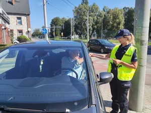 Zdjęcie, na którym policjantka wręcza medal wzorowego kierowcy dla kierującego samochodem osobowym.
