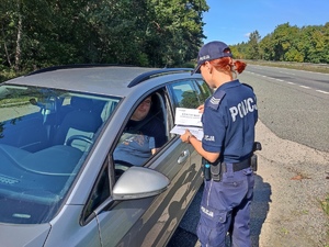 Zdjęcie, na którym policjantka wręcza certyfikat wzorowego kierowcy.