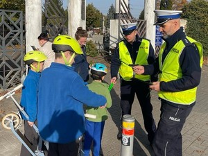 Na zdjęciu umundurowani policjanci rozdają odblaski.