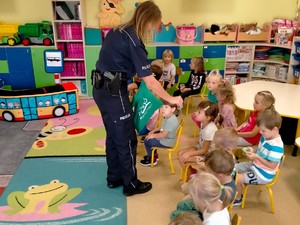 Na zdjęciu policjantka rozdaje dzieciom odblaski w przedszkolu.