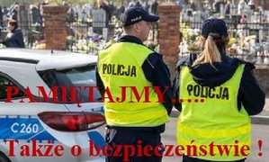 Zdjęcie. Na pierwszym planie, odwróconych tyłem,  stoi dwoje umundurowanych policjantów przy cmentarzu. Na zdjęciu widnieje napis Pamiętajmy także o bezpieczeństwie.