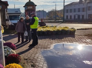 Policjant w okolicy cmentarza rozdaje odblaski.