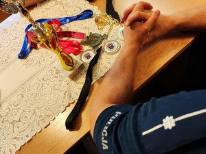Na zdjęciu widać pagon policyjny oraz puchar i medale ustawione na stole.