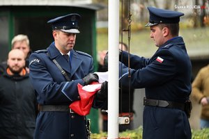 Na zdjęciu widoczni policjanci wciągający flagę na maszt.