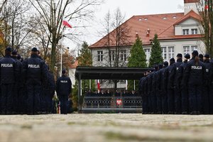 Zdjęcie grupowe, na którym znajdują się nowi policjanci oraz w oddali kierownictwo śląskiej Policji.