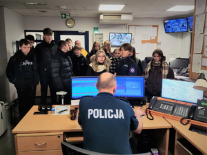 Na zdjęciu grupa młodzieży zwiedza pomieszczenie będzińskiego dyżurnego Policji.