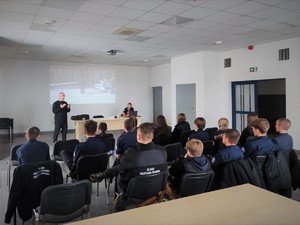 Zdjęcie, na którym technik kryminalistyki prowadzi zajęcia przed grupą młodzieży.