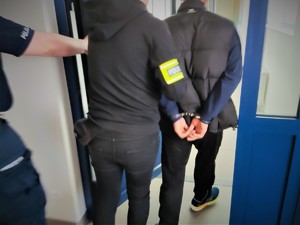 Na zdjęciu policjant wyprowadza mężczyznę z policyjnego aresztu.