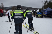 Dwóch policjantów w kombinezonach narciarskich z napisem POLICJA na stoku.