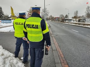 Policjanci ruchu drogowego w kamizelkach odblaskowych obserwują ruch na drodze