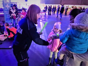 Na zdjęciu policjantka rozdaje odblaski kobiecie z dziećmi.