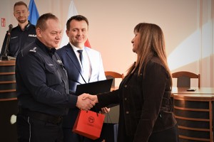 Komendant Powiatowy Policji w Będzinie wraz ze Starostą Będzińskim przekazują upominki odchodzącej na emeryturę policjantce.
