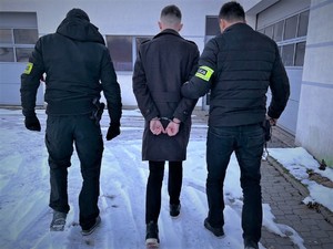 Na zdjęciu policjanci prowadzą zatrzymanego.