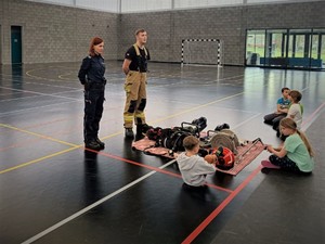 Na zdjęciu policjantka i strażak przed dziećmi.