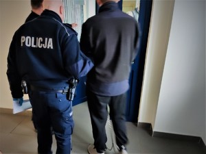 Na zdjęciu policjant trzyma zatrzymanego mężczyznę.