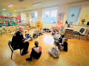Zdjęcie, na którym policjant rozmawia z dziećmi w sali.