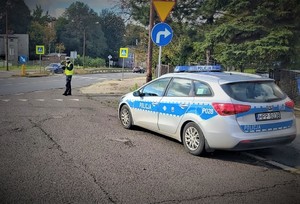 Na zdjęciu policjant stoi z urządzeniem do mierzenia prędkości przy przejściu dla pieszych.