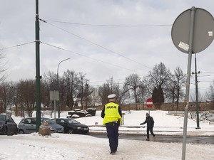 Na zdjęciu policjant podchodzi do mężczyzny, który przechodzi przez przejście dla pieszych.