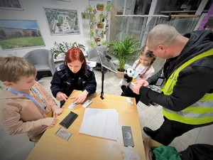 Na zdjęciu policjanci pobierają od dzieci odciski palców.