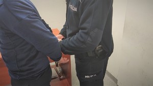 Zdjęcie, na którym policjant zakłada zatrzymanemu kajdanki.